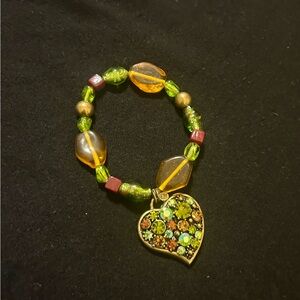 Beaded bracelet in green and deep yellow with a stone heart charm. Stretchy.